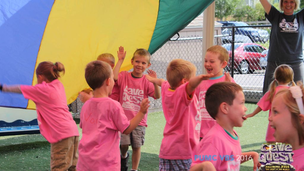 VBS Kids Running and Laughing under a parachute during game time