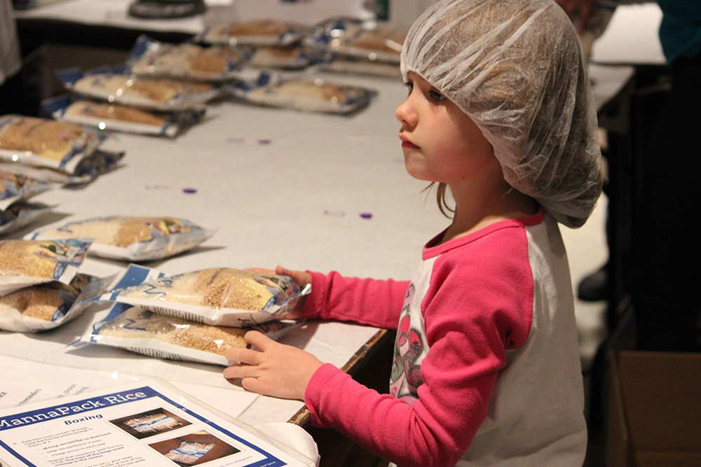 Little girl packing food at FMSC Mobile Pack 2015