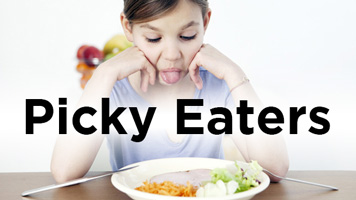 Girl sticking her tongue out at a plate of vegetables